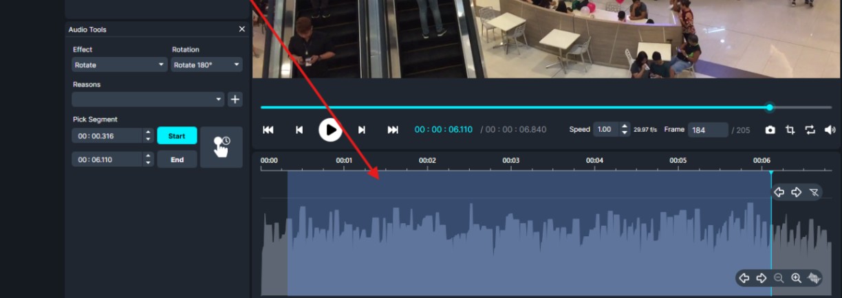 Video editor screenshot: play controls above a blue timeline and a blue audio waveform with a red arrow pointing to a segment.