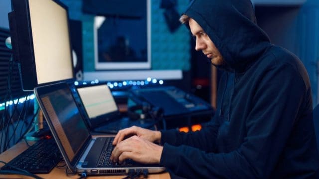 Hacker sitting at laptop, information hacking