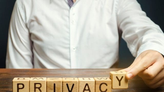 Businessman puts wooden blocks with the word Privacy. Keeping secret information about a person's personality or activity and financial condition. Safety and security. Business and finance concept