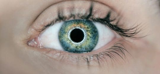 Close up of a woman's blue eye with a ring of light around her iris.