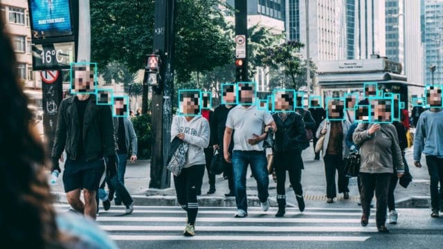 Redacted photo of people walking down the street with faces blurred