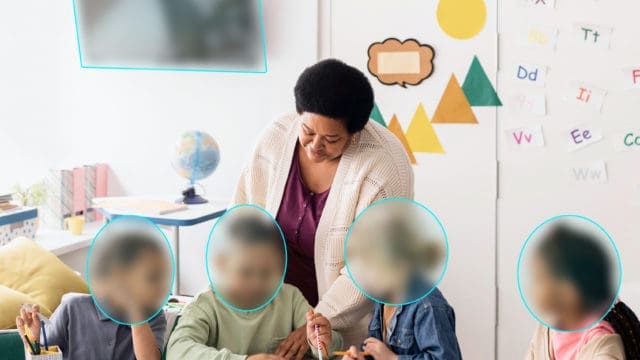 A teacher helping her students who are all redacted